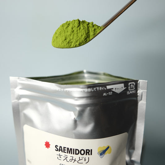 Spoon with green powder next to a package labeled 'Saemidori' on a light gray background