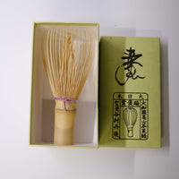Wooden whisk in a green box with branding on a white background